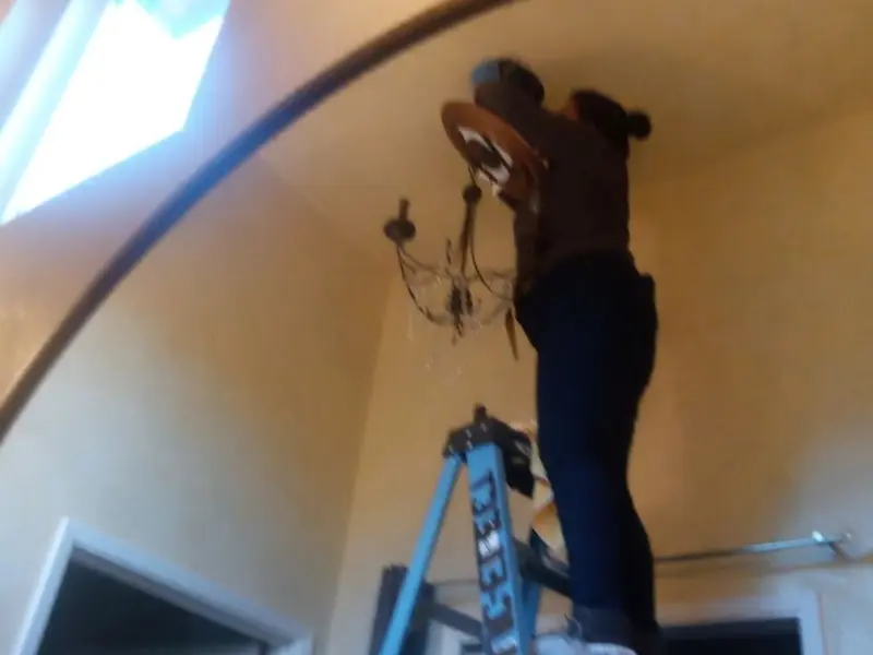 Electrician installing a chandelier in a Aubrey residence